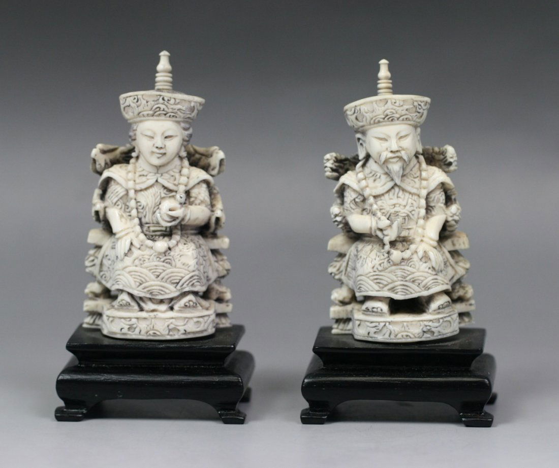 A Pair Of Chinese Carved Emperor And Empress: A Pair of Chinese Carved Emperor and Empress: elaborately carved, each with ornate robes and headdresses: he of dragon motif and clasping his beaded necklace in one hand: she of phoenix motif and hold