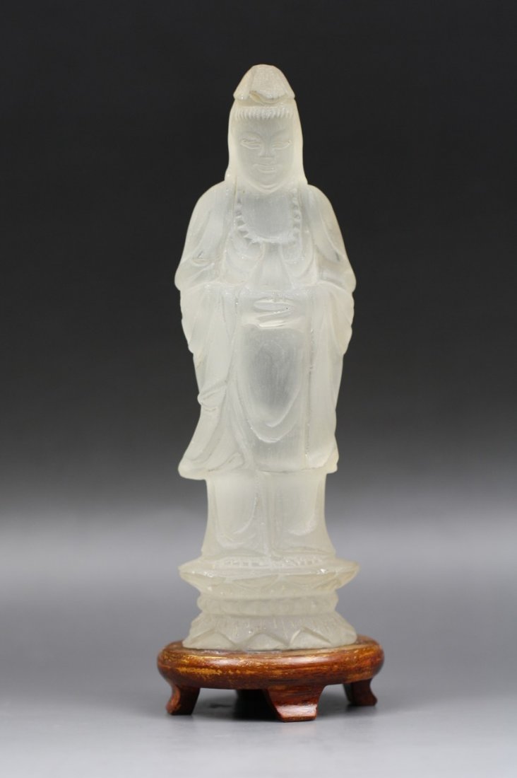 A Rock Crystal Figure of Guanyin: A Rock Crystal Figure of Guanyin: carved from the material with translucent pure color of white as a Guanyin wearing a beaded necklace while standing in flowing robes on a double lotus plinth, present