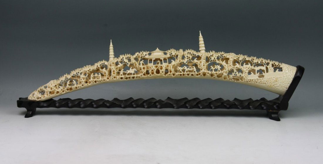 A Chinese Carved Ivory Bridge: A Chinese Carved Ivory Bridge: finely pierced carved with figures in typical openwork landscape scene with two towers and one pavilion, attached on fancy wood stand; Size: L: 24"(i)