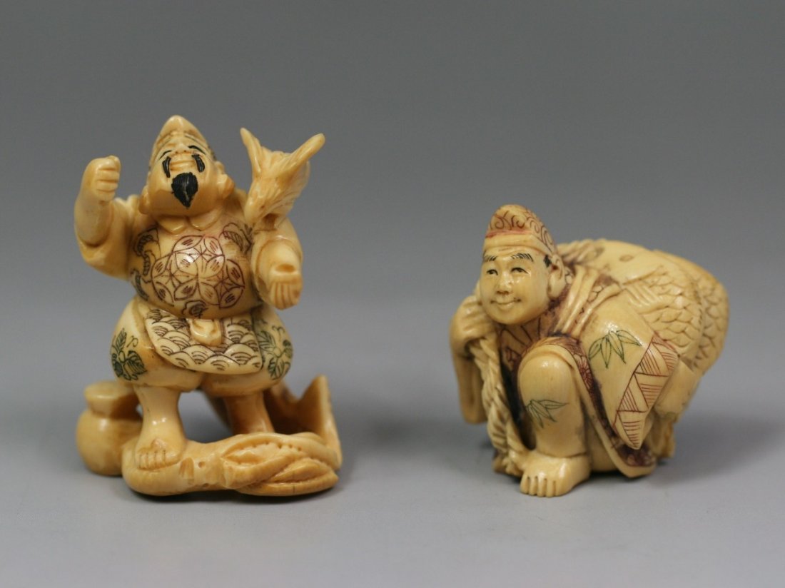 Pair Of Antique Polychrome Ivory Netsukes: Pair of Antique Polychrome Ivory Netsukes: one man standing with a bird perched on his left shoulder while a fish lays behind him, a man dressed in a robe kneels with one leg while carrying fish on a