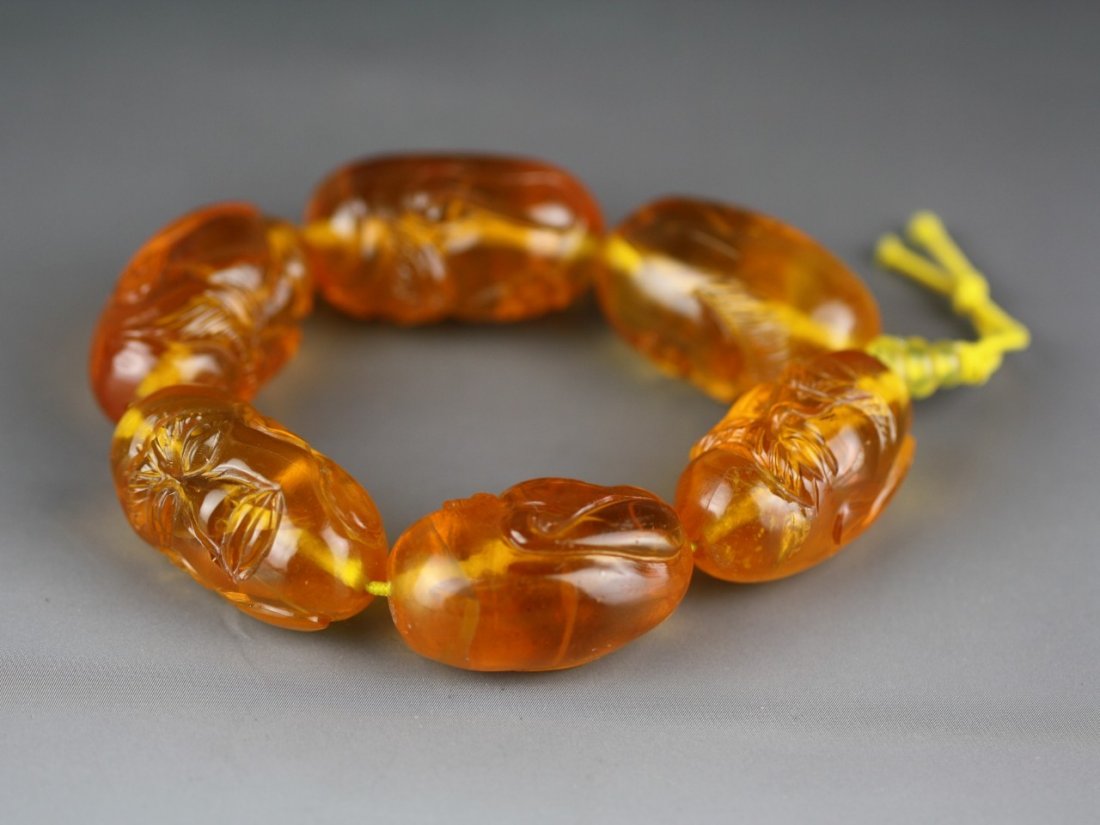 An Amber Bracelet: An Amber Bracelet: comprised of six big ovoid amber beads carved with Lohan/Arhat heads, material of translucent warm brown color ; Size: D:80MM X BEADS:6