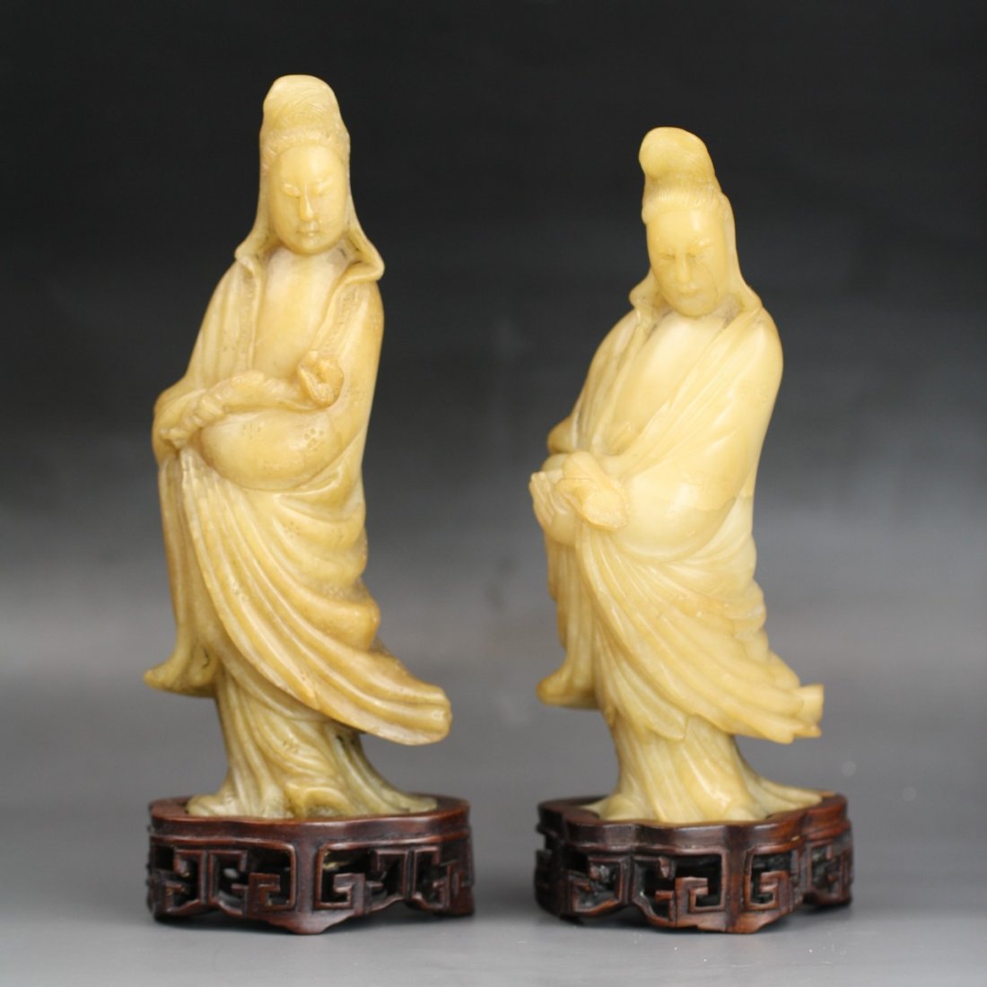 Pair Of Chinese Soapstone Carvings Of Guanyin: Pair Of Chinese Shoushan Soapstone Carvings Of Guanyin: both carved from the Shoushan soapstone of pale ochre color as Guanyin standing in flowing robes, with matching wood stands, of Minguo period; S