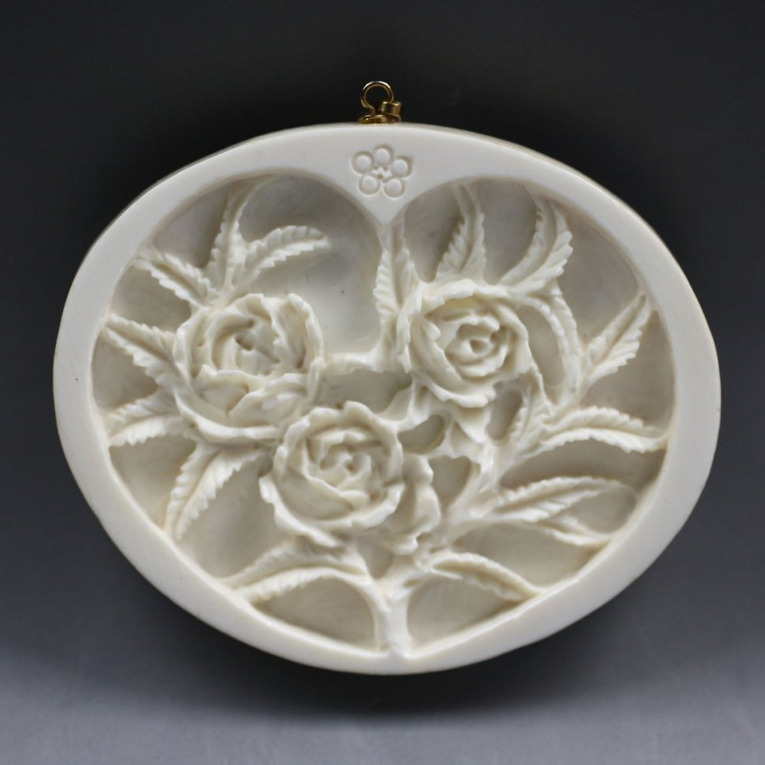 A Chinese Carved Ivory Plaque: A Chinese Carved Ivory Plaque: of oval shape, finely carved on one side in the center with the panel of three blossoms with foliage; Size: H:2-3/8"; W:2-3/4"