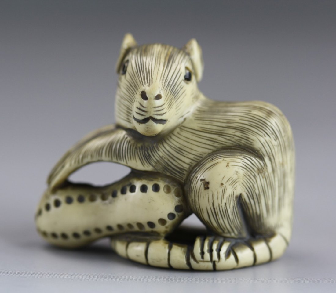 An Antique Ivory Netsuke: Mouse: An Antique Ivory Netsuke: A highly detailed mouse resting upon a nut, its tail is wrapped around, Signature located on its tail; Size: H: 1-5/8"; L: 1-3/4"