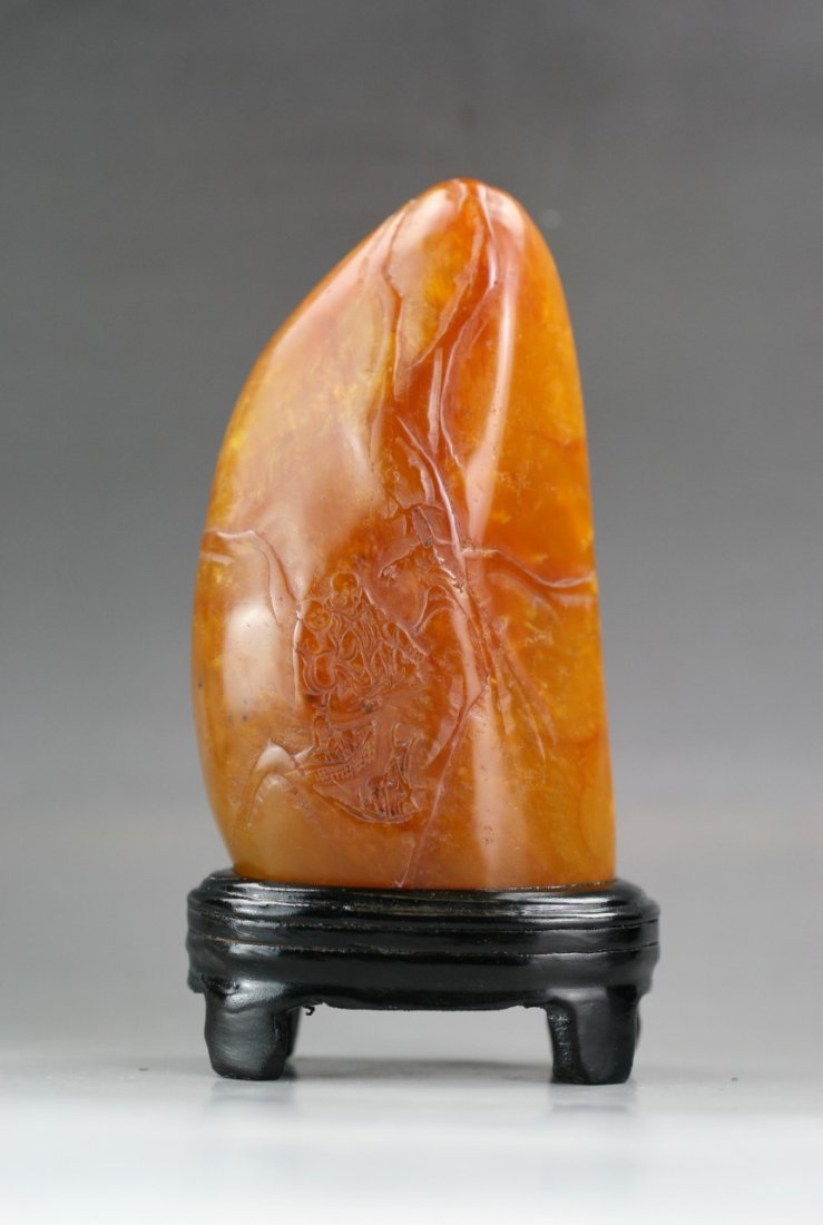 A Tianhuang-Like Stone Carving: A Tianhuang-Like Stone Carving: of irregular rectangular form, carved from the stone of semi-translucent ochre tone, Minguo period or later, on matching wood stand; Size: L: 8" ; H: 3-1/4"