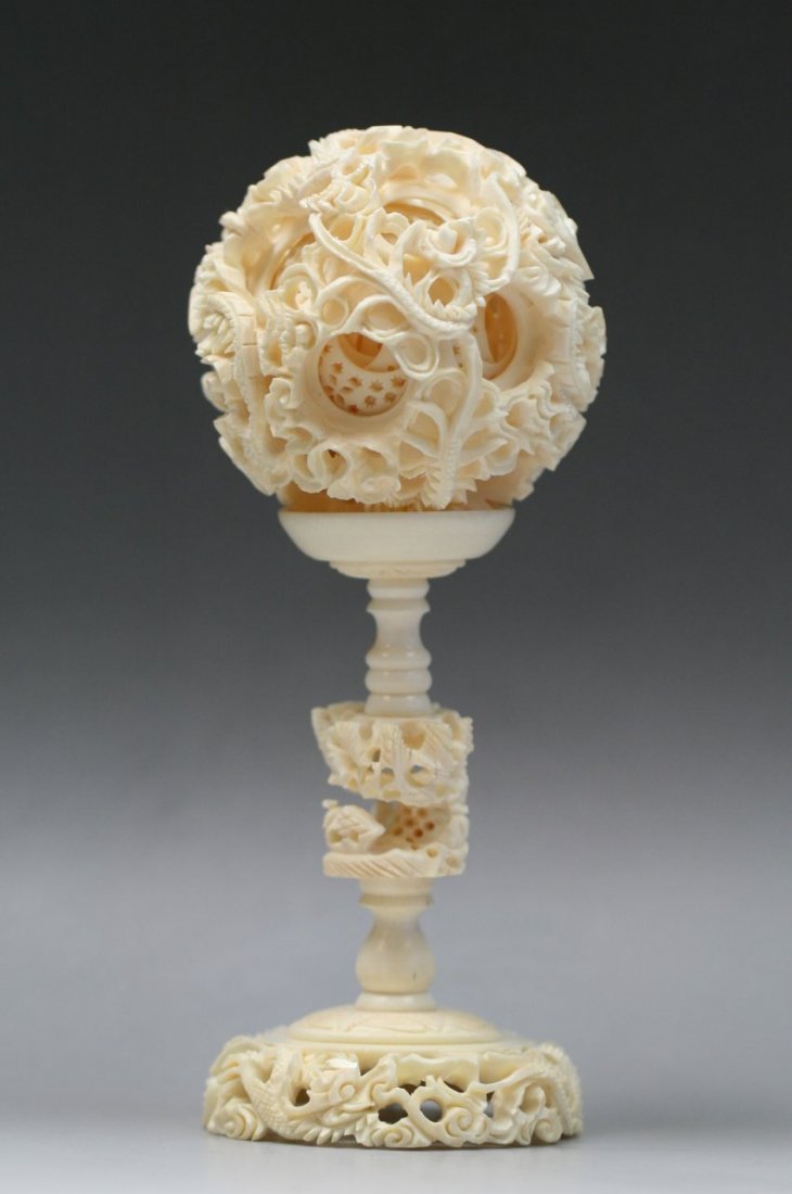Chinese Carved Ivory Puzzle Ball And Stand: Chinese Carved Ivory Puzzle Ball And Stand: carved with dragons and blossoms to the exterior, and at least fourteen inner concentric openwork balls supported by a pedestal stand, of Minguo period; Siz