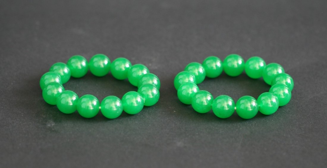 Pair Green Jade/Jadeite Bracelets: Pair Green Jade/Jadeite Bracelets: comprised of beads carved and polished from the semi-translucent jade or jadeite with brilliant green tone, each bead approximately 12mm in diameter; Size: D: 3-1/2"
