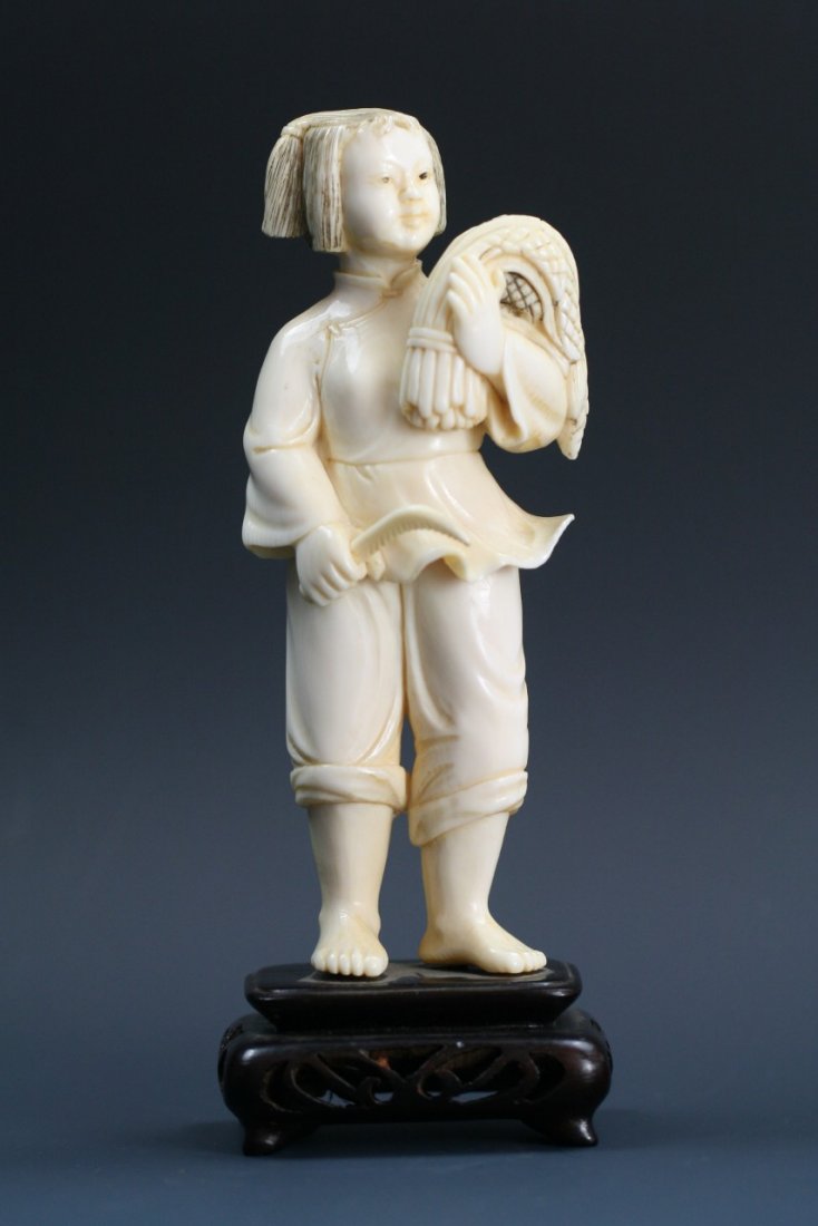 A Chinese Cultural Revolution Carved Ivory Figure: A Chinese Cultural Revolution Carved Ivory Figure: carved as a girl standing and holding a bushel of millet, attached to wood stand; Size: H: 5"