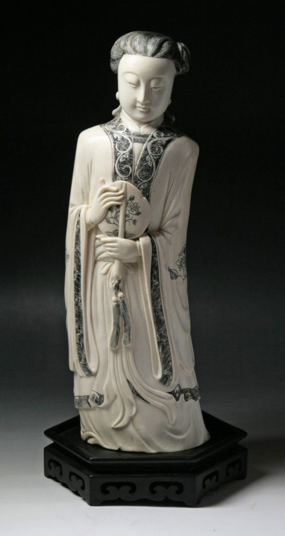 A Big And Fine Chinese Antique Ivory Beauty: A Big And Fine Chinese Antique Ivory Beauty: finely carved as a beauty standing in layered robes carrying a fan in her hands, of late Qing Dynasty, on a dark wood stand probably Zitan; Size: (Ivory) H