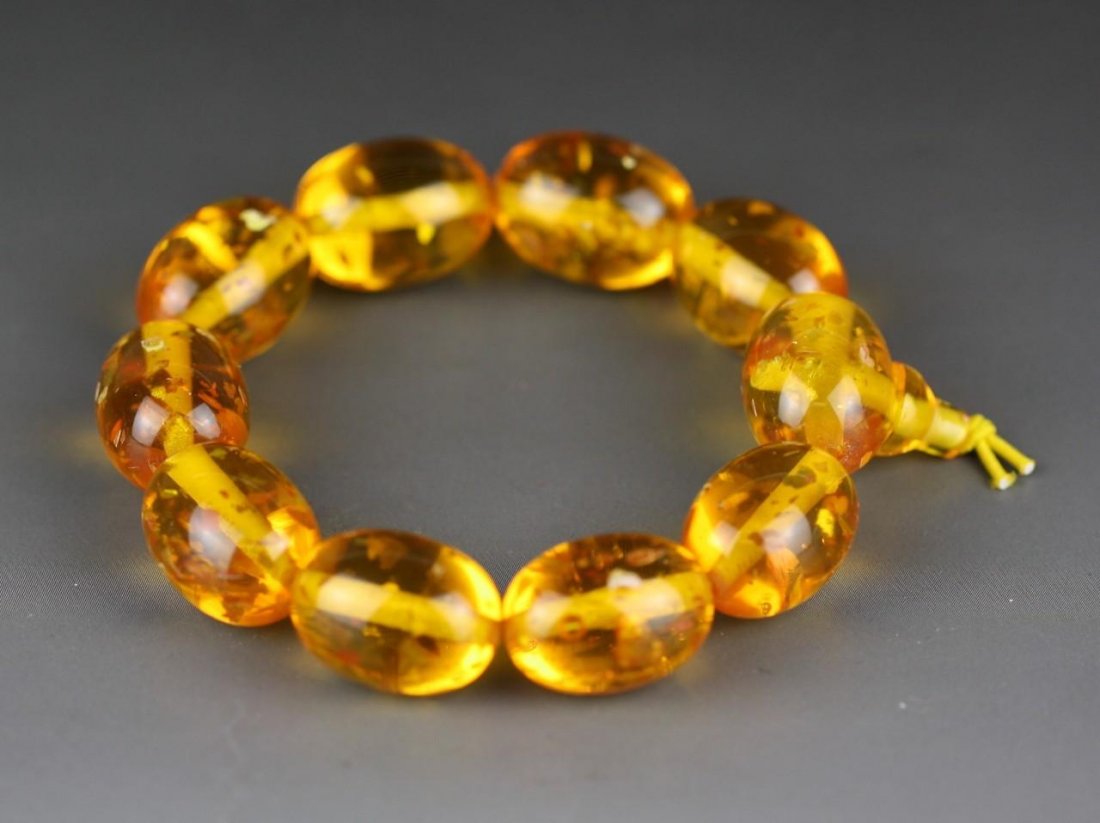 An Amber Bracelet: An Amber Bracelet: comprised of ten oval shaped amber beads of translucent bright brown tone with natural inclusions; Size: D: 75MM X BEADS; 10