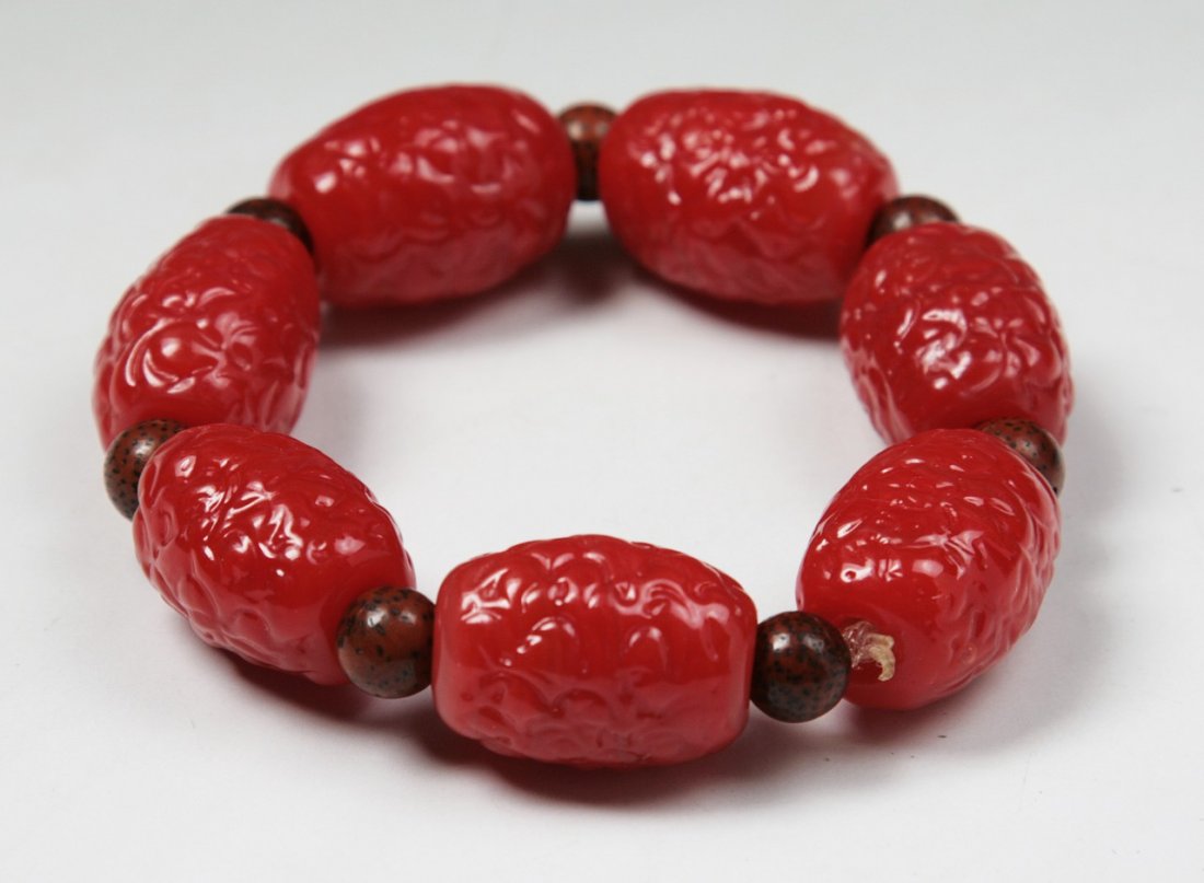 A Chinese Antique Peking Glass Bracelet: A Chinese Antique Peking Glass Bracelet: comprised of seven (7) well carved Peking glass beads of red tone measuring approximately 20mm by 13mm each; Size: Beads: 20X13mm; D: 3-1/2"