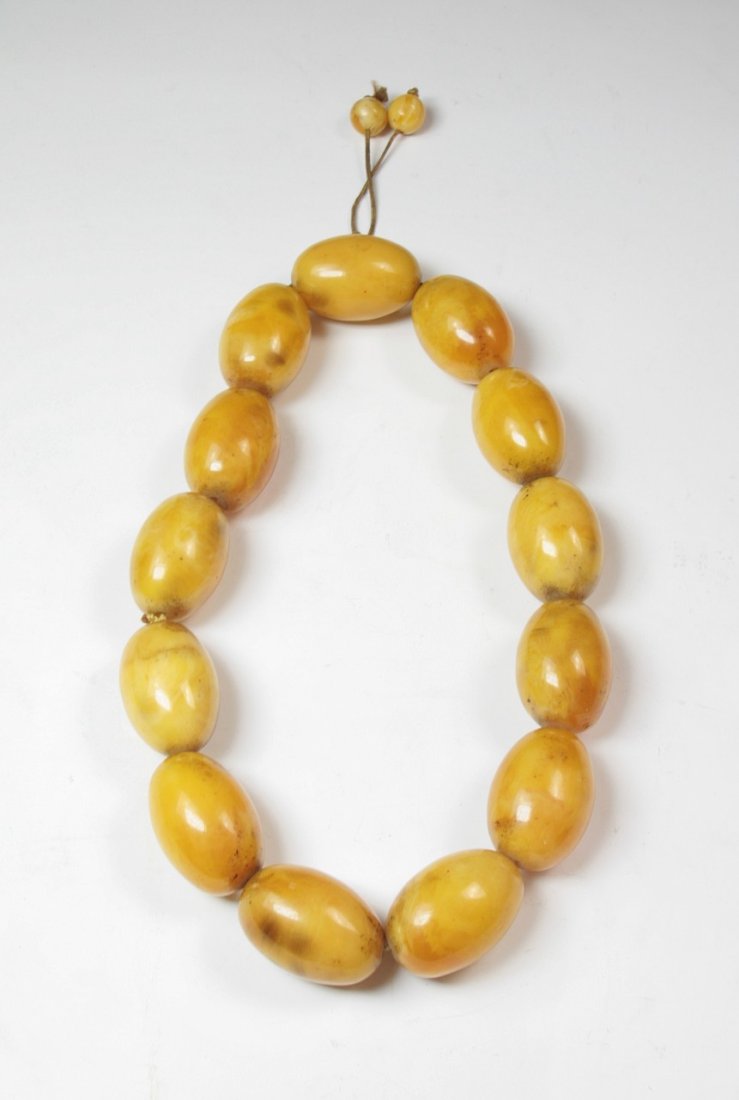A Massive Chinese Amber Necklace: A Massive Chinese Amber Necklace: comprised of fourteen massive beads carved from amber with caramel tone measuring approximately 45mm each and weighing approximately 285g; Size: Beads L: 45mm; Overal