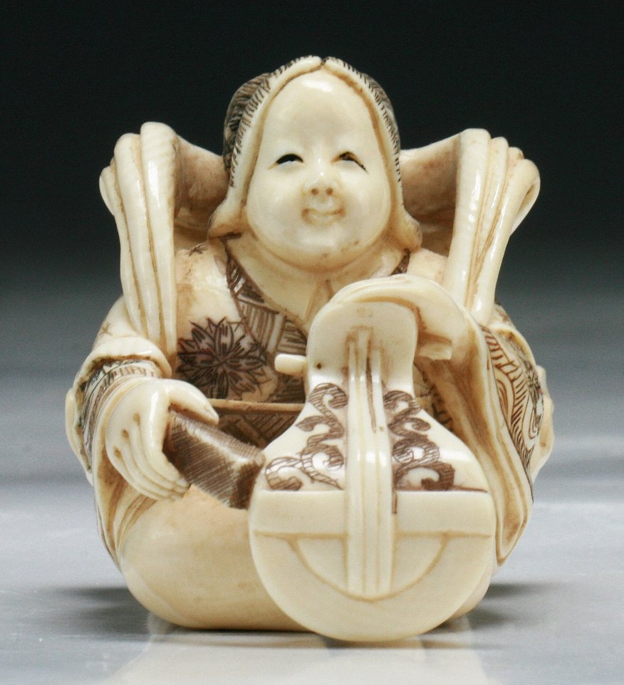 A Japanese Antique Carved Ivory Netsuke Lady: 象牙根付 A Japanese Antique Carved Ivory Netsuke Lady: finely polychromed and carved as a lady musician playing her instrument while wearing long and layered robes, signed on t