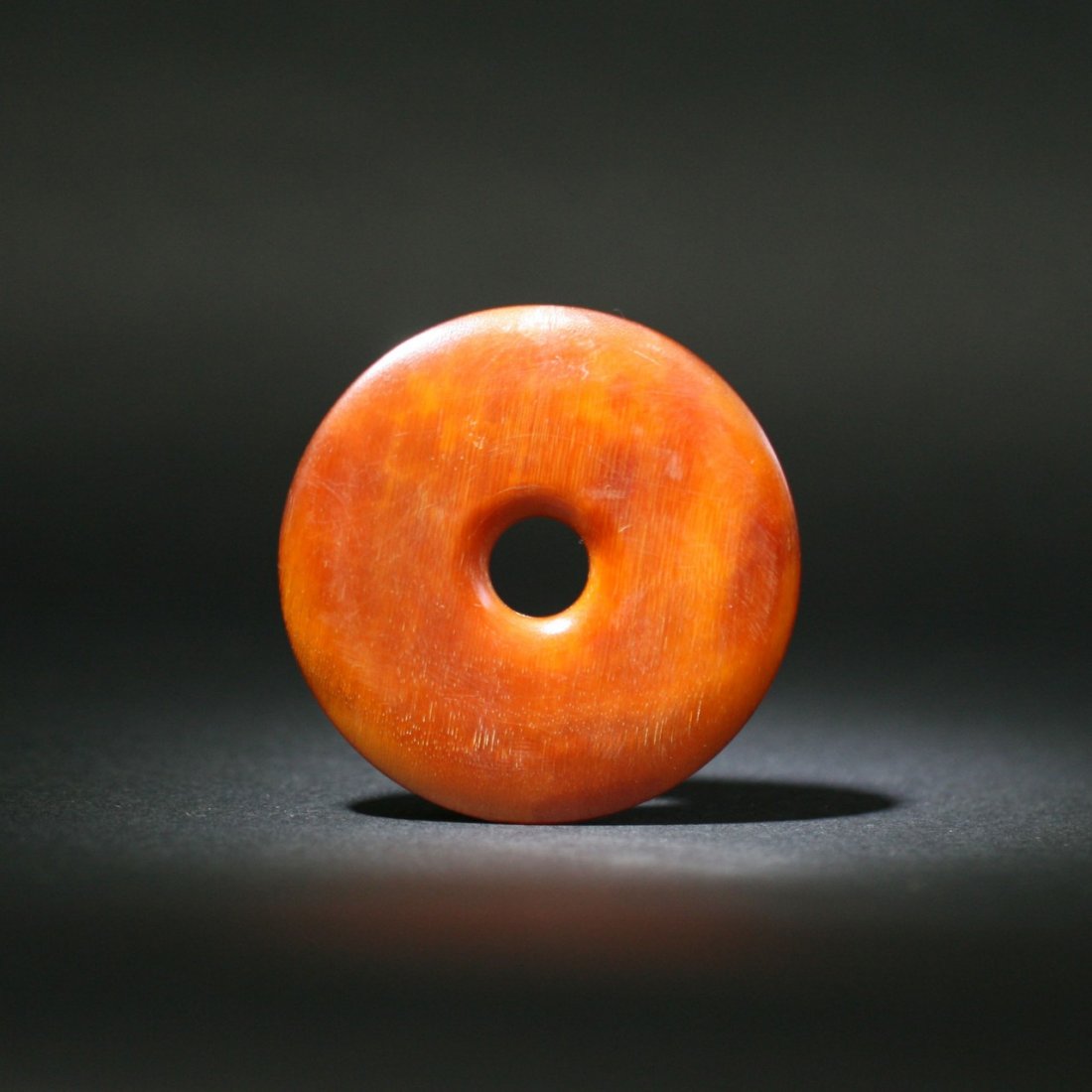 A Chinese Antique Carved Horn Pendant: A Chinese Antique Carved Horn Pendant: of circular form with a small hole in the center, finely carved from the rhinoceros horn or like with attractive reddish brown tone; Size: D: 60mm