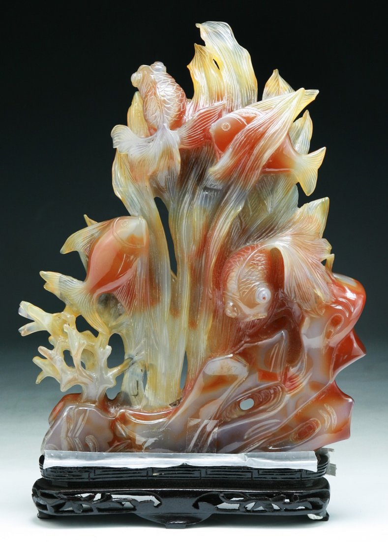 A Chinese Agate Fish Group Carving: A Chinese Agate Fish Group Carving: finely carved from the agate as the scene of fish swimming amid weeds, presented on a wood stand; Size: H: 11-1/4" (overall)