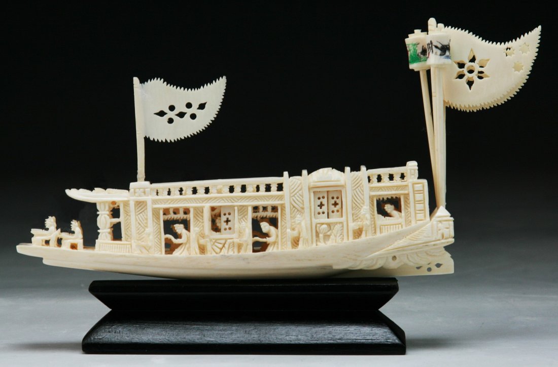 A Chinese Antique Ivory Carved Boat: A Chinese Antique Ivory Carved Boat: finely pierced carved as a boat decorated with flags with figures in leisure, presented on a wood stand; Size: L: 6"; H: 4-1/2" (overall)