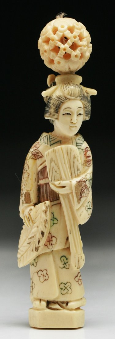 A Japanese Antique Carved Ivory Beauty: A Japanese Antique Carved Ivory Beauty: carved as a beauty standing in robes with a puzzle ball on her head, signed on the base; Size: H: 3-3/4"