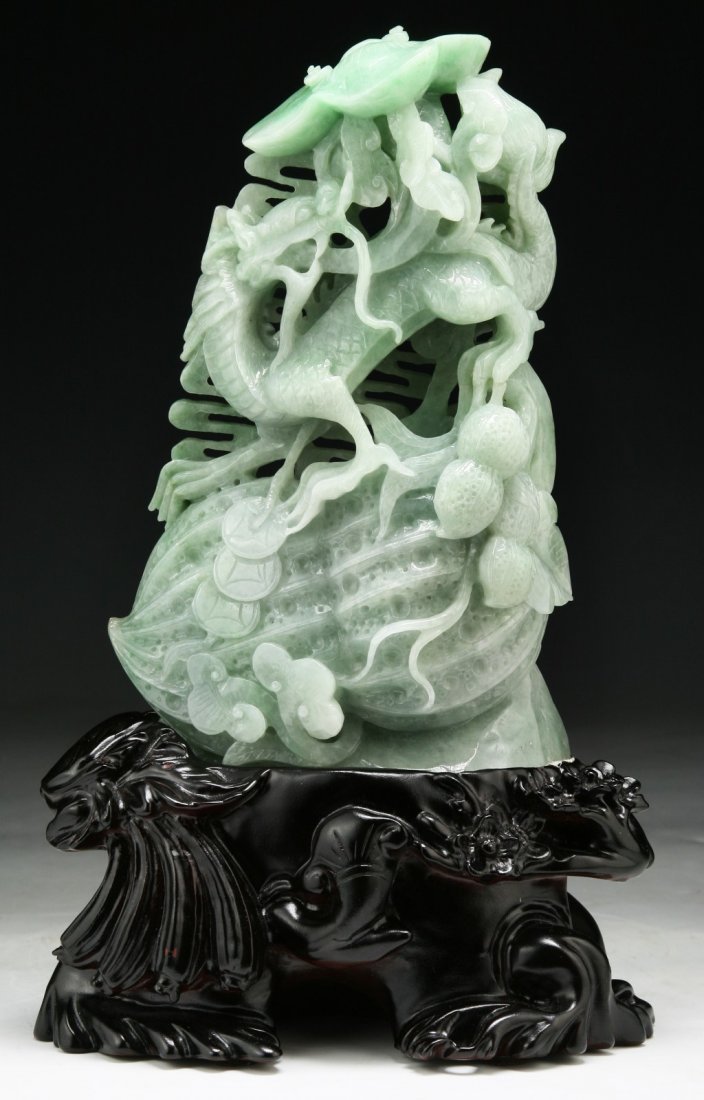 A Chinese Jadeite Carved Dragon Group: A Chinese Jadeite Carving Group: finely carved in deep relief from the translucent jadeite of pale green tone with apple green areas as a encircling dragon amid cloud scrolls and ling zhi, presented o
