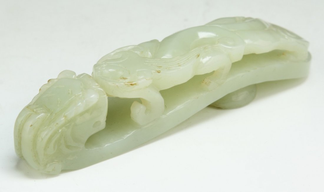 A Chinese Antique Nephrite White Jade Buckle: A Chinese Antique Nephrite Jade Buckle: antique nephrite white jade, finely carved as a dragon head and body meeting at the center; of late 19th Century; Size: L: 4-1/4"