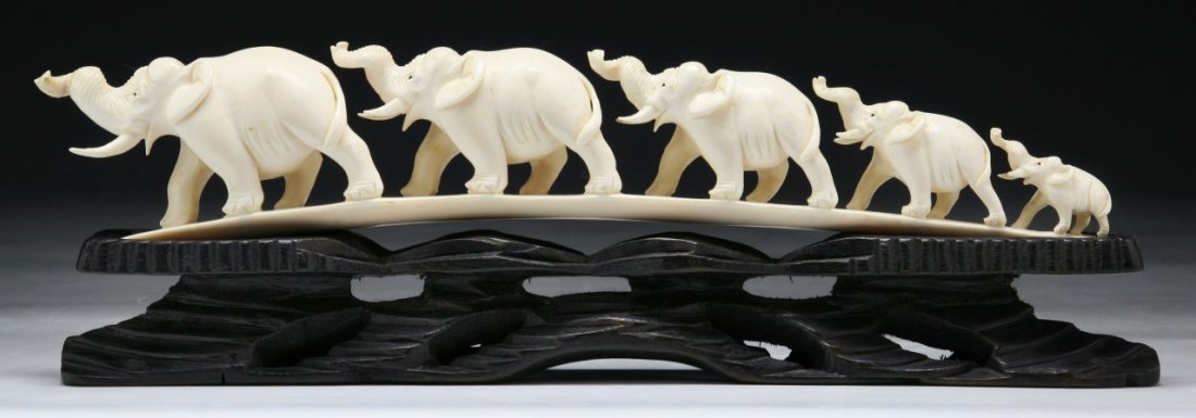 A Chinese Antique Carved Ivory Elephant Group: A Chinese Antique Carved Ivory Elephant Group: with five elephants of graduating size walking in a line with their trunks up, presented on a fancy wood stand, African ivory, Late Qing Dynasty (19th Ce