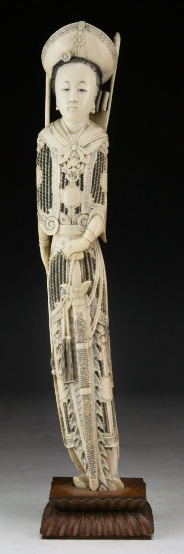 A Chinese Antique Ivory Carved Beauty: A Chinese Antique Ivory Carved Beauty: standing in a long elaborate flowing robe with a large headpiece holding a sword with both hands; presented on a wood stand, African ivory, Late Qing Dynasty (19
