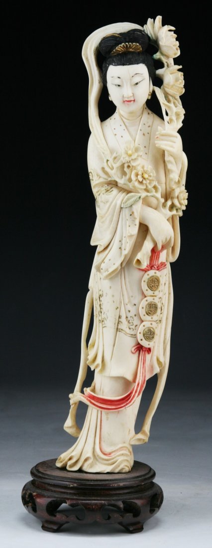 A Chinese Antique Polychrome Ivory Beauty: A Chinese Antique Polychrome Ivory Beauty: finely detailed beauty standing in swaying robes holding a large branch of blooming flowers in both hands; presented on a wood stand, Asian ivory, Late Qing