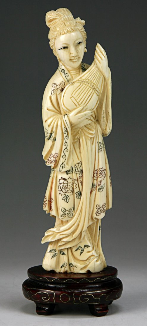 A Japanese Antique Polychrome Ivory Carved Beauty: A Japanese Antique Polychrome Ivory Carved Beauty: finely carved as a beauty in decorative robes holding an instrument with both hands, presented on a wood stand, African ivory, early 20th Century, NO