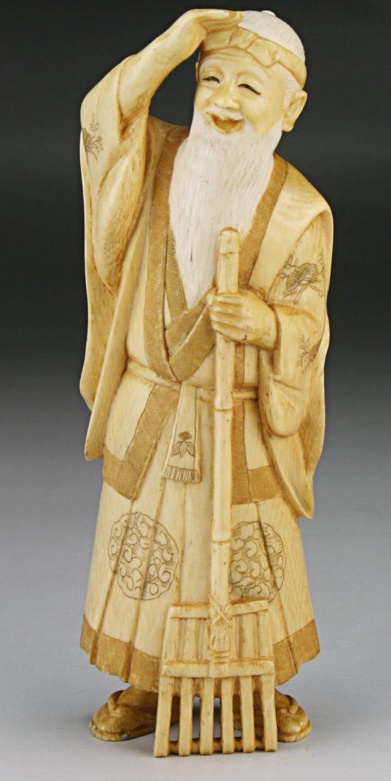 A Japanese Antique Ivory Carved Figure: A Japanese Antique Ivory Carved Figure: finely carved as a man in layered decorative robes holding a long rake in his left hand while the other hand rest above his head, African ivory, early 20th Cent