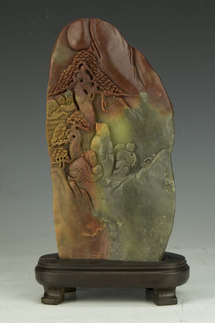 A Chinese Soapstone Carved Mountain: A Chinese Soapstone Carved Mountain: finely carved with three men surrounded by rockery and trees, presented on a wood stand; Size: H: 9"; (overall) H: 10-1/8"
