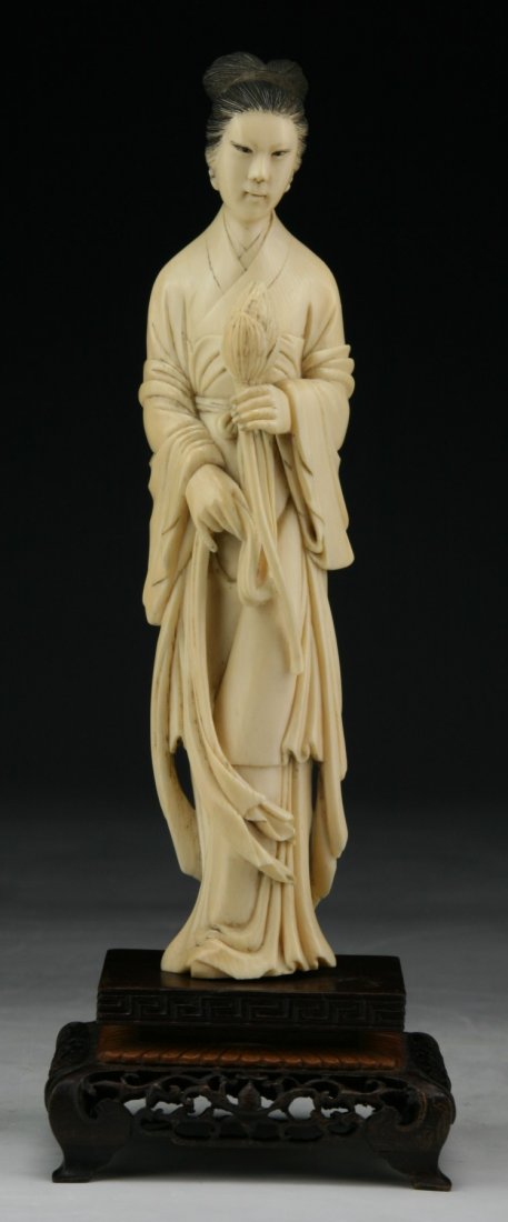 A Chinese Antique Ivory Carved Beauty: A Chinese Antique Ivory Carved Beauty: finely carved as a beauty standing in a long flowing robe holding ribbons in both hands, presented on a wood stand, of Middle Qing Dynasty, NO INTERNATIONAL SHIP