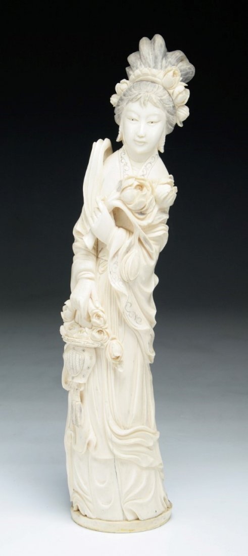 A Chinese Antique Carved Ivory Beauty: A Chinese Antique Carved Ivory Beauty: carved as a beauty standing in layered robes wearing high headdresses carrying a basket full of flowers while other hand holding a big blossom, African ivory, La