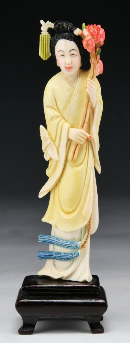 A Chinese Antique Polychrome Ivory Carved Beauty: A Chinese Antique Polychrome Ivory Carved Beauty: finely carved as a beauty standing in swaying robes holding a large blooming branch, presented on a wood stand, African ivory, of 19th Century, NO INT