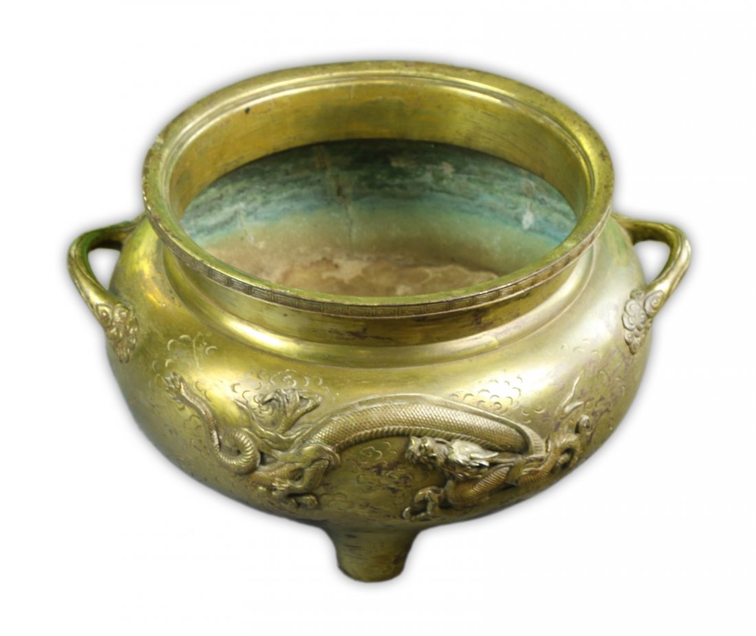 A Chinese Antique Bronze Tripod Censer: A Chinese Antique Bronze Tripod Censer: the compressed body rested on three low feet, the rim surmounted by two loop handles, the body finely cast in high relief with a dragon and a phoenix in flight;