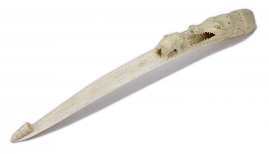 A Chinese Antique Ivory Carved Tusk: A Chinese Antique Ivory Carved Tusk: finely carved with an elephant leading to an alligator head with its mouth open, African ivory, circa 1900; Size: L: 21”