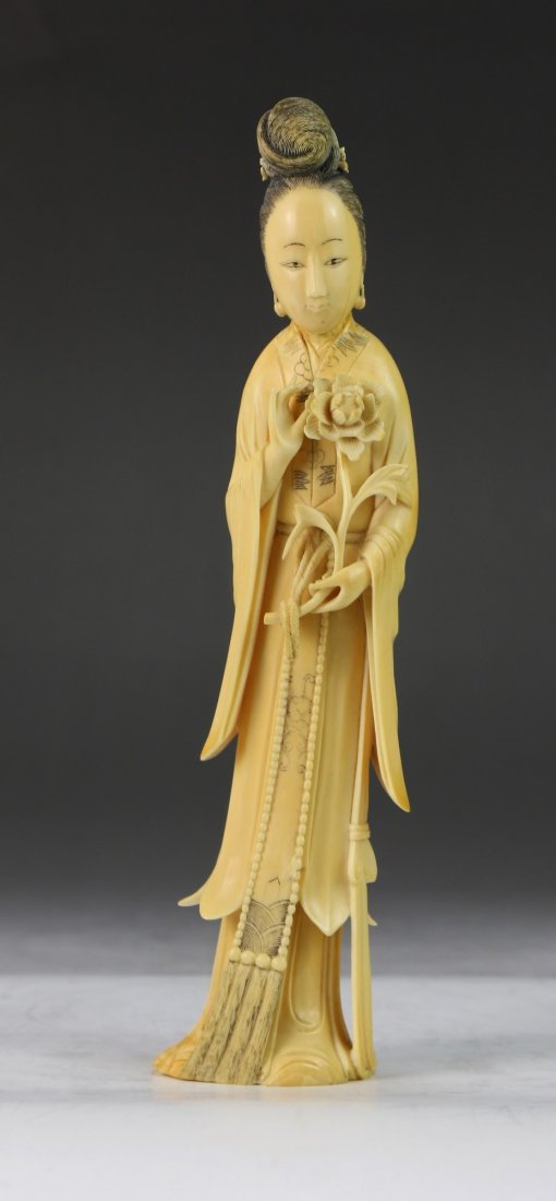 A Chinese Antique Ivory Carved Beauty: A Chinese Antique Ivory Carved Beauty: finely carved as a beauty in long robes with a decorative belt holding a blooming branch, presented on a wood stand, African ivory, Late Qing Dynasty (19th Centu