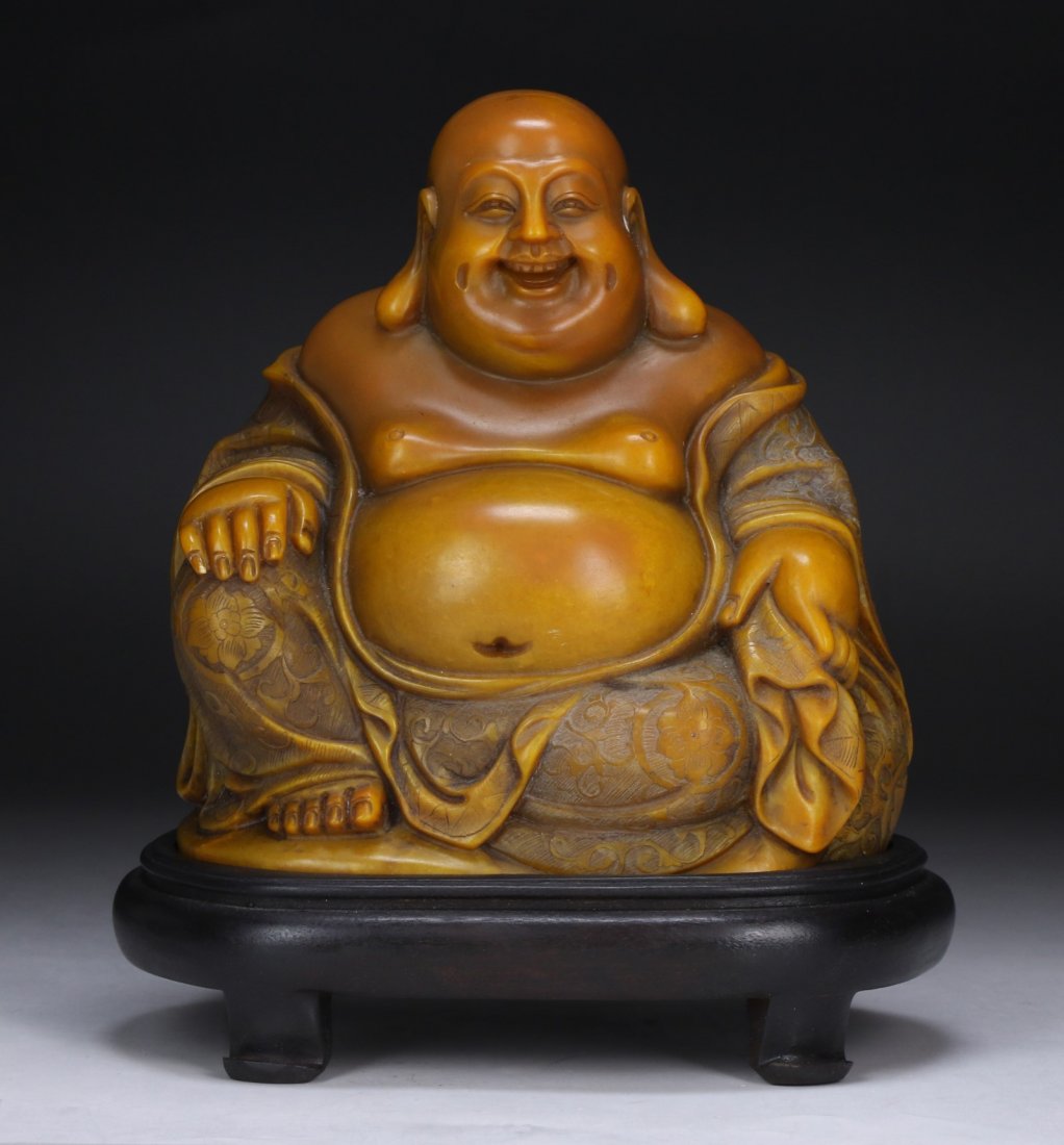A Chinese Soapstone Carved Buddha: A Chinese Soapstone Carved Buddha: finely carved as Buddha in a seated position, presented on a wood stand; Size: H: 7"; (overall) H: 8-1/4"