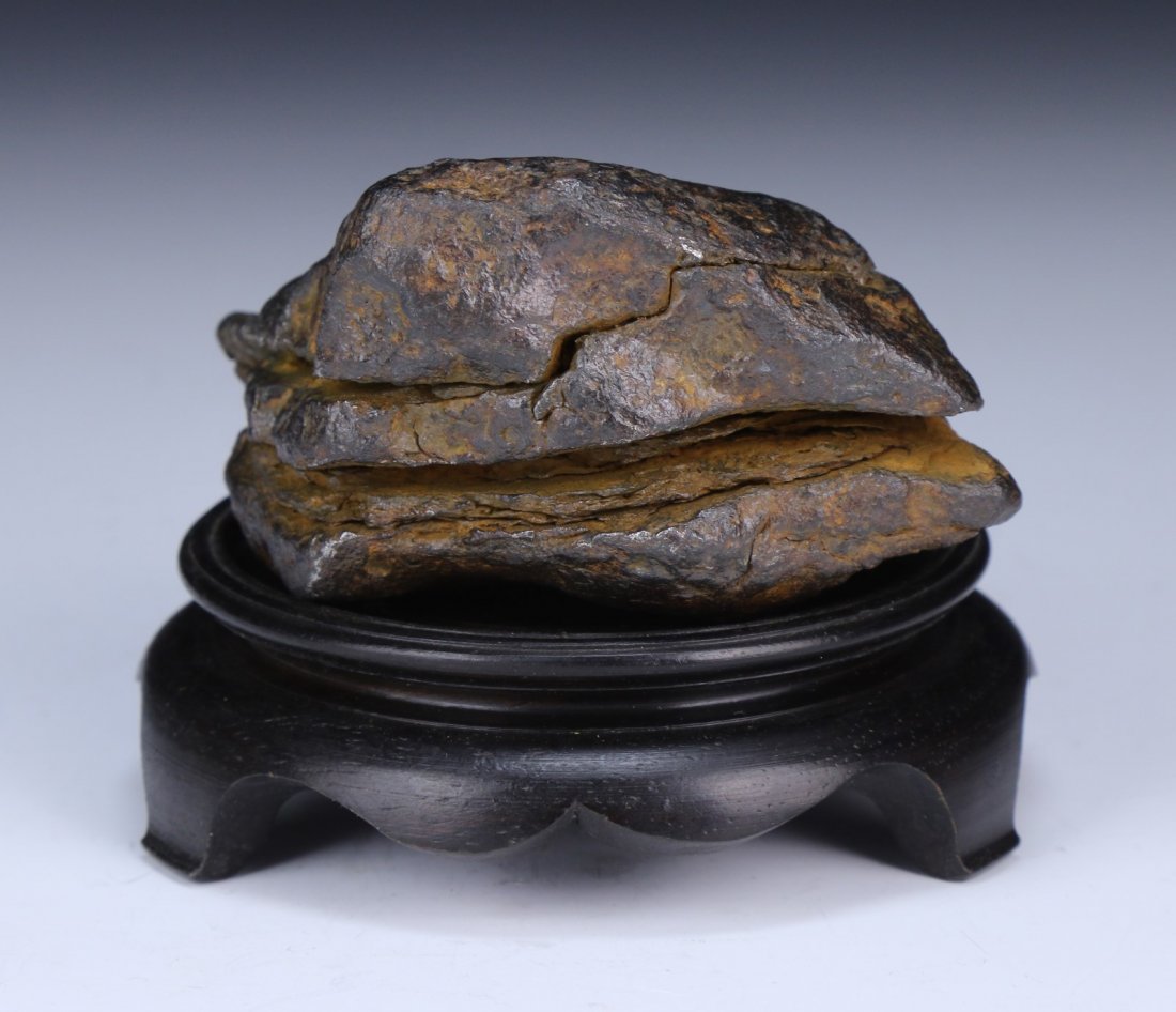 A Natural Meteorite Rock: A Natural Meteorite Rock: the stone with rusty brown color, weighing 720 grams, presented on a wood stand; Size: L: 4" (stone); Weight: 720 grams