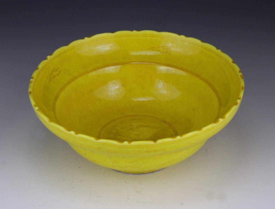 A Chinese Antique Yellow Glazed Porcelain Bowl: A Chinese Antique Yellow Glazed Porcelain Bowl: the exterior with cranes flying amid clouds, with an all over yellow glaze; Size: D: 6-3/4"