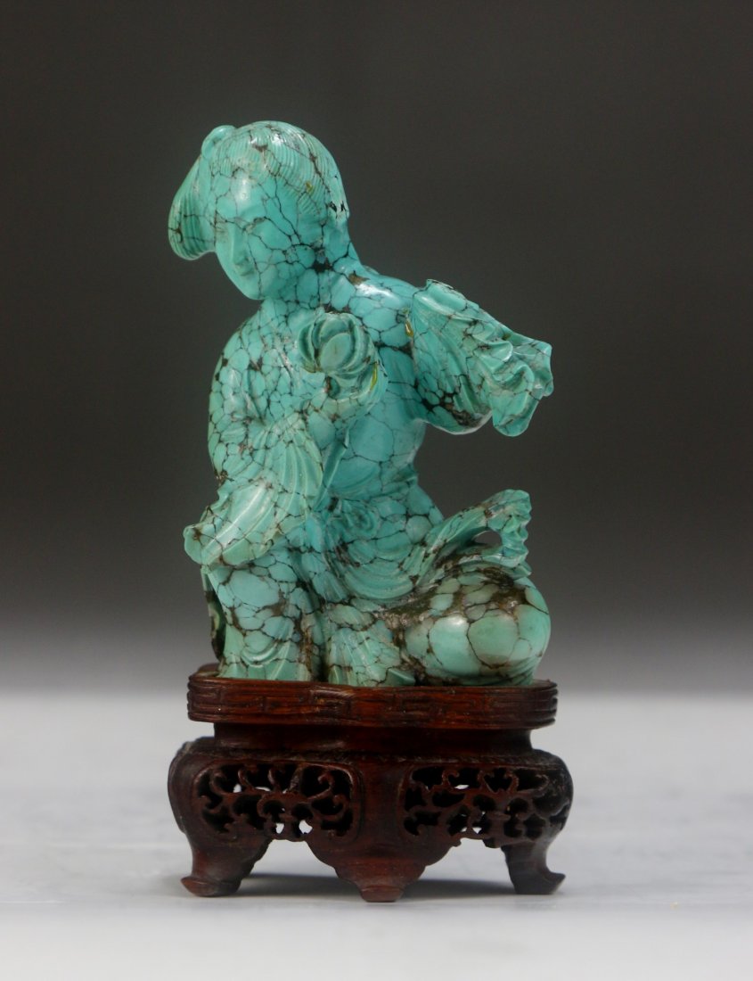 A Chinese Antique Turquoise Carved Beauty: A Chinese Antique Turquoise Carved Beauty: finely carved as a beauty resting on her knees in long robes holding a flower, presented on a wood stand, of QING Dynasty; Size: H: 4"