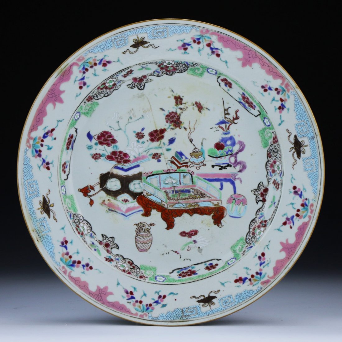 A Chinese Antique Famille Rose Plate: A Chinese Antique Famille Rose Plate: Of The Yongzheng Period, Displaying An Elegant Room With A Chair And Vases With Blooming Flowers; Size: D: 11-1/4" (29cm)