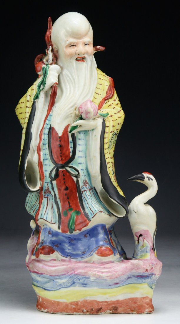 A BIG CHINESE ANTIQUE FAMILLE ROSE PORCELAIN SHOU: A Big Chinese Antique Famille Rose Porcelain Shou Figure: Shown Standing in Traditional Robes Next To A Crane, Carrying A Long Knotted Staff in His Right Hand, And A Peach in His Left; Size: H: 13-1/2