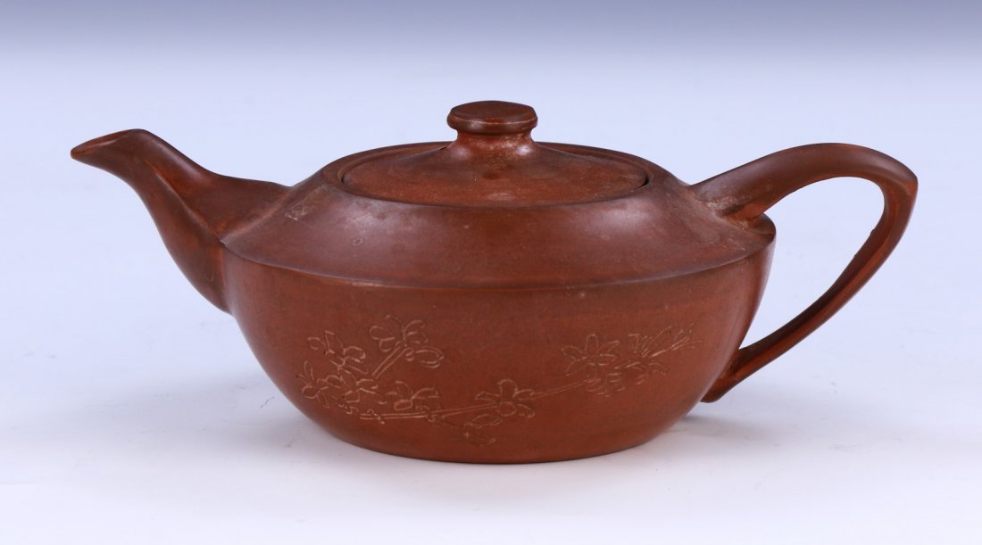 A Chinese Antique Zisha Teapot: A Chinese Antique Zisha Teapot: Of Curved Shouldered Form, Curling Handle On One Side, A Small And Cylindrical Spout Flanking The Other, One Side Of The Body Finely Carved With A Subtle Blooming Flowe