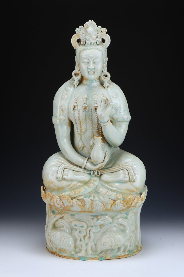 A CHINESE ANTIQUE YUAN DYNASTY BLANC-DE-CHINE YINGQING: A Chinese Antique Yuan Dynasty Blanc-De-Chine Yingqing Glazed Porcelain Guanyin: Presented With Elongated Lobes, in A Seated Position, On Top Of A Stand Carved With Various Fish; Size: H: 22-3/4" (57.