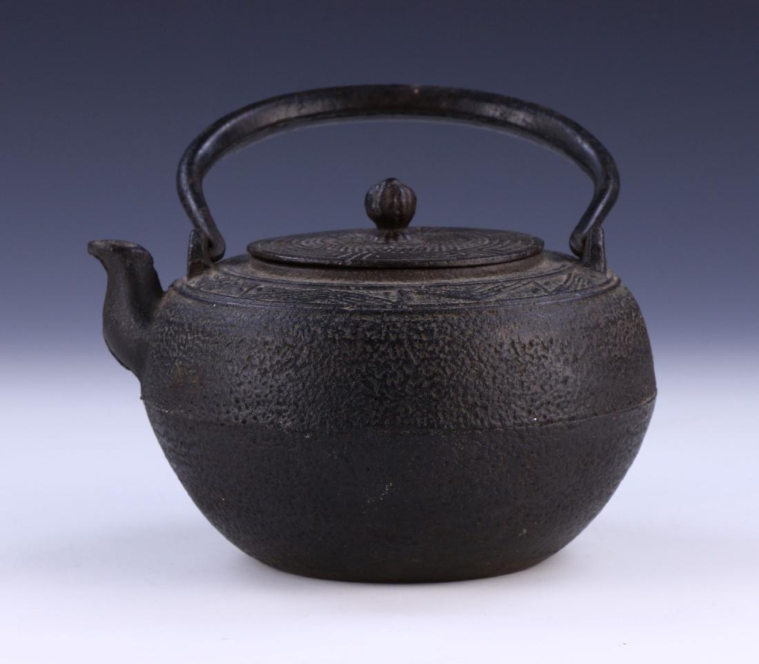 A JAPANESE ANTIQUE IRON TEAPOT: A Japanese Antique Iron Teapot: Of Globular Form, Rising To A Flat Lid, Body Finely Cast With Squared Geometric Patterns; Size: L: 7" (17.78cm)