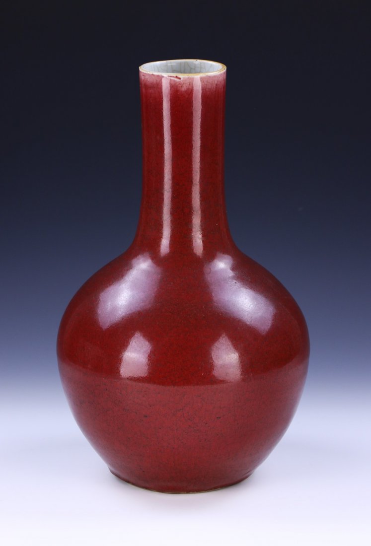 A CHINESE ANTIQUE OX BLOOD PORCELAIN VASE: A CHINESE ANTIQUE OX BLOOD PORCELAIN VASE: of globular form rising to a cylindrical neck, the body evenly coated in an ox blood enamel glaze; Size: H: 15" (38.1cm)