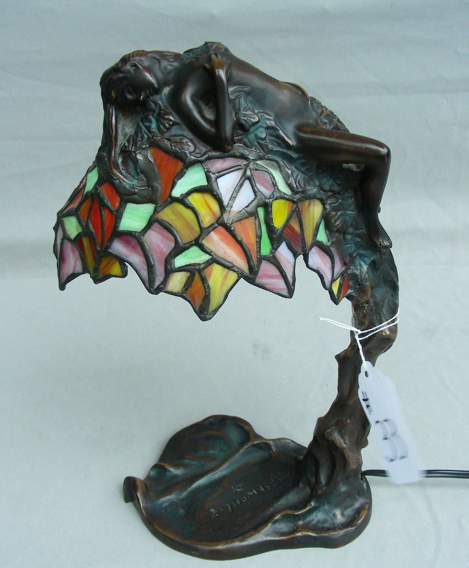 BEAUTIFUL SMALL SCALE BRONZE & LEADED GLASS LAMP: A domed leaded glass lamp supports a reclining nude woman. Fine detail. 12 1/2" high.