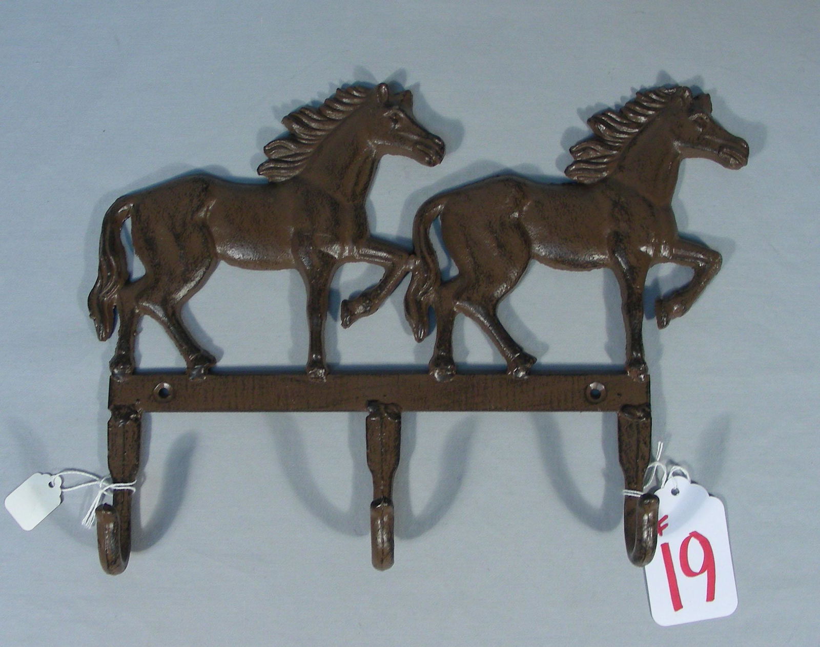 HEAVY CAST IRON HORSE MOTIF WALL RACK: Two running horses with three hooks. 9 1/2" high, 13" wide.