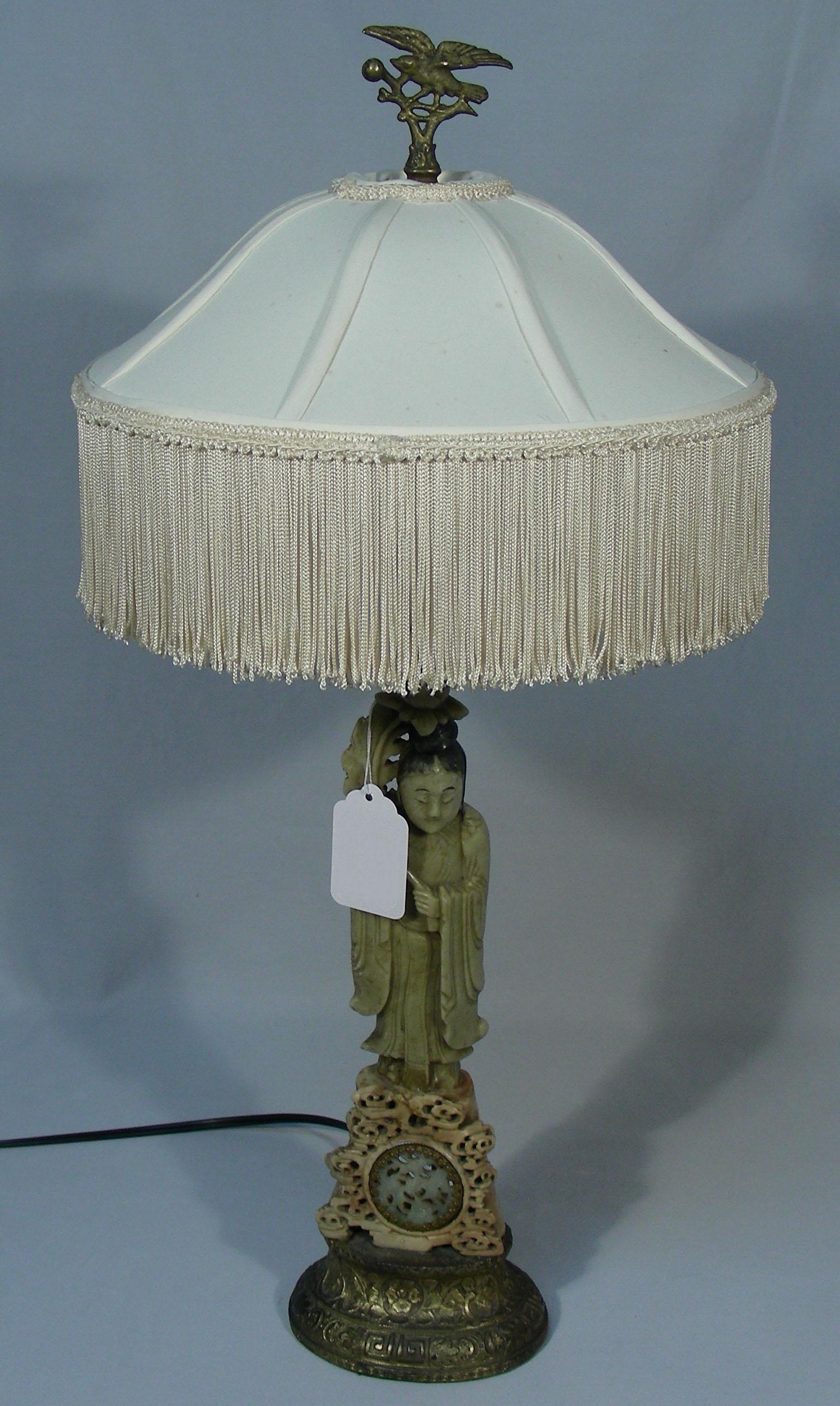 ANTIQUE CHINESE FIGURAL SOAPSTONE TABLE LAMP: An antique metal base supports a standing geisha supporting linen shade. 26 1/2" high.