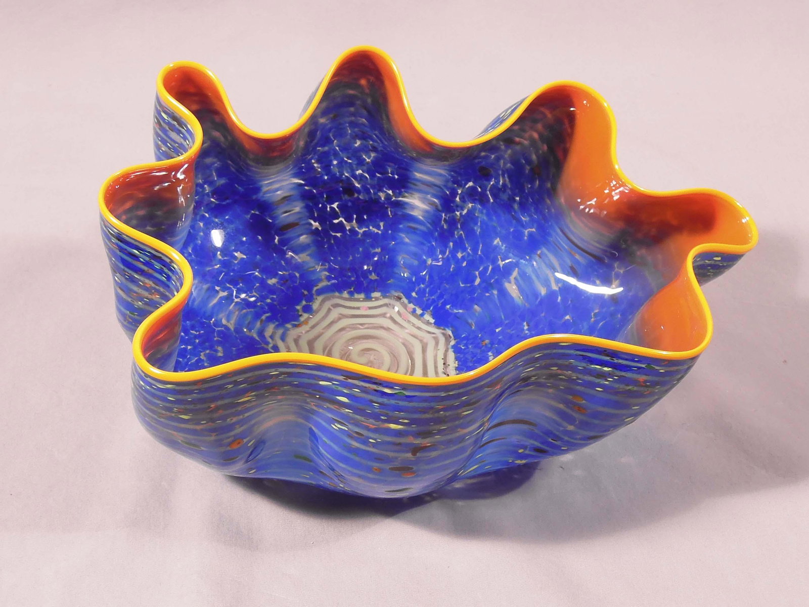 DALE CHIHULY (1941- ) AMERICAN: Original blown art glass "Alla Macchia" bowl. Orange & blue coloration. Excellent condition. Hand signed on base. Plexiglass case included along with original book and cleaner (unopened). 5" high, 10"