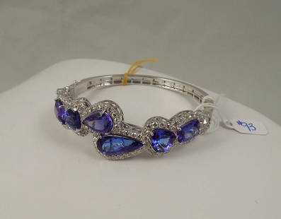 OUTSTANIDING LADIES 18K W.G., TANZANITE & DIAMOND BANGLE BRACELET: A highly polished white gold bangle set with very fine tanzanites (cushion cut, triangular, pear shaped and heart shaped). Total Tanzanite weight 27.51 cts. Each tanzanite surrounded by a single row o